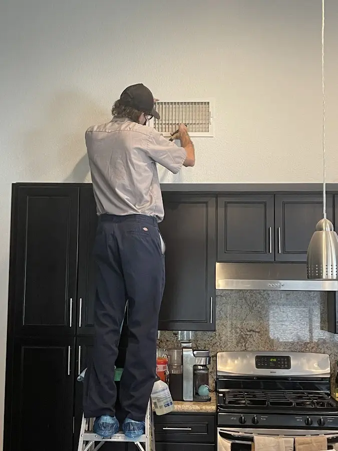Technician inspecting an air vent during HVAC service in Frankfort